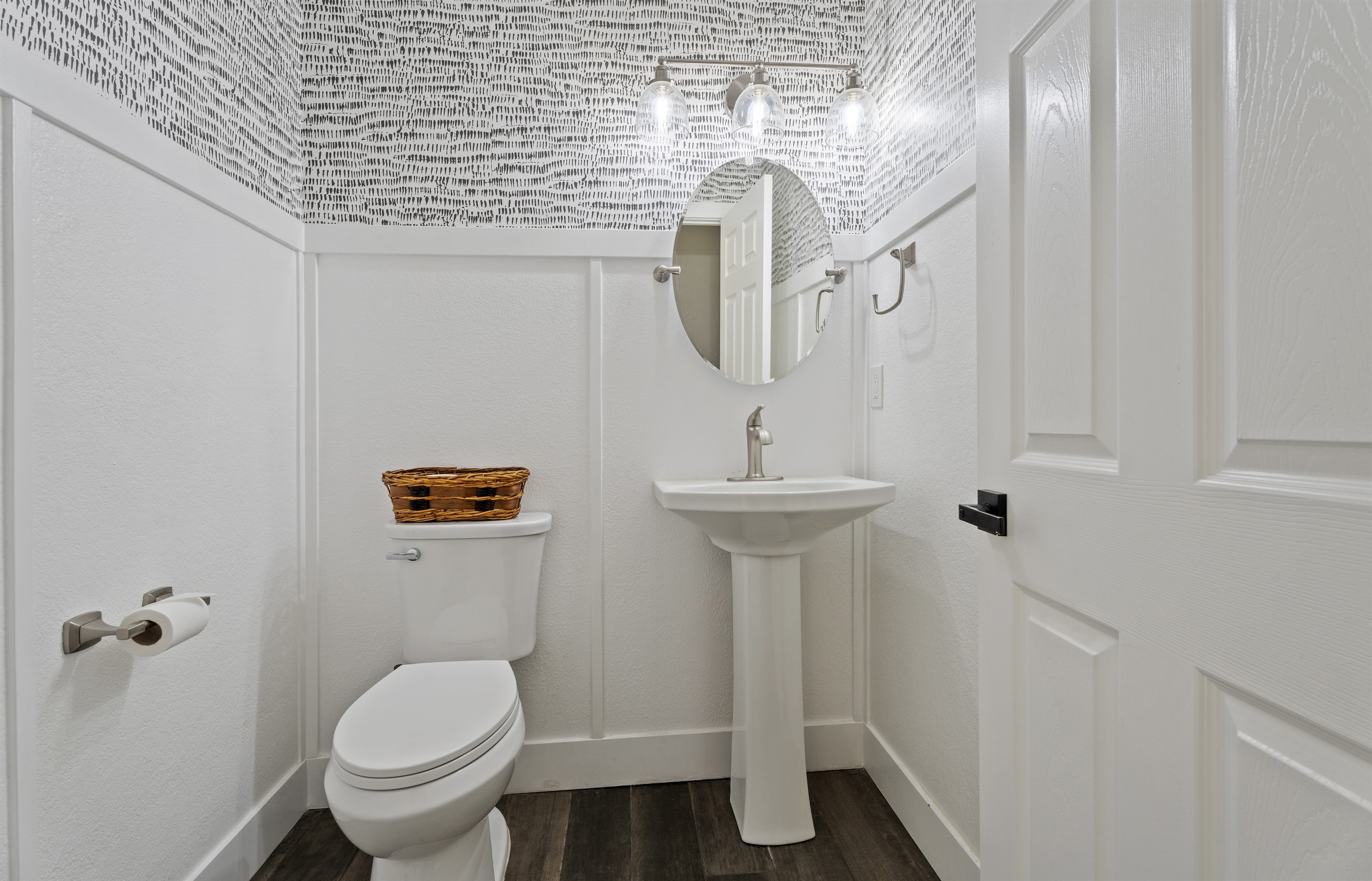 Modern and artistic, this half bath features sleek fixtures, eye-catching wallpaper, and a clean, polished design.