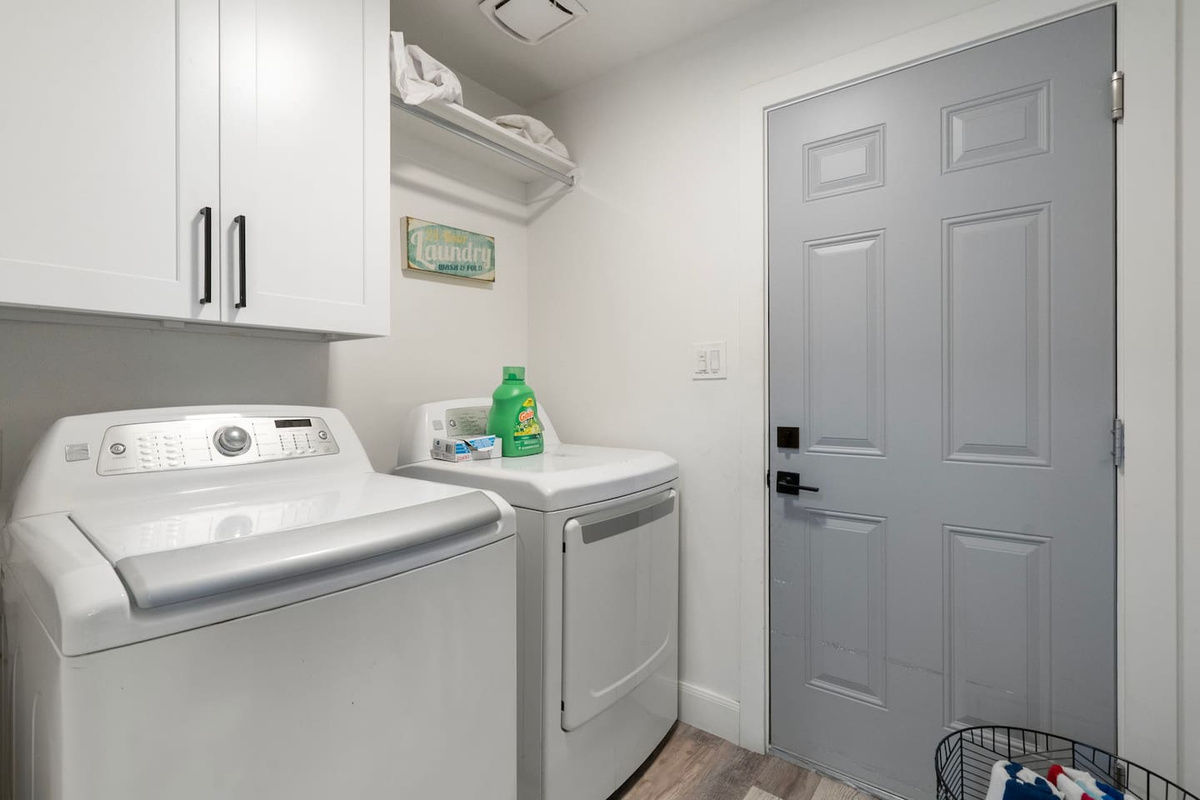 Modern laundry room with full-size washer and dryer, storage, and utility sink.