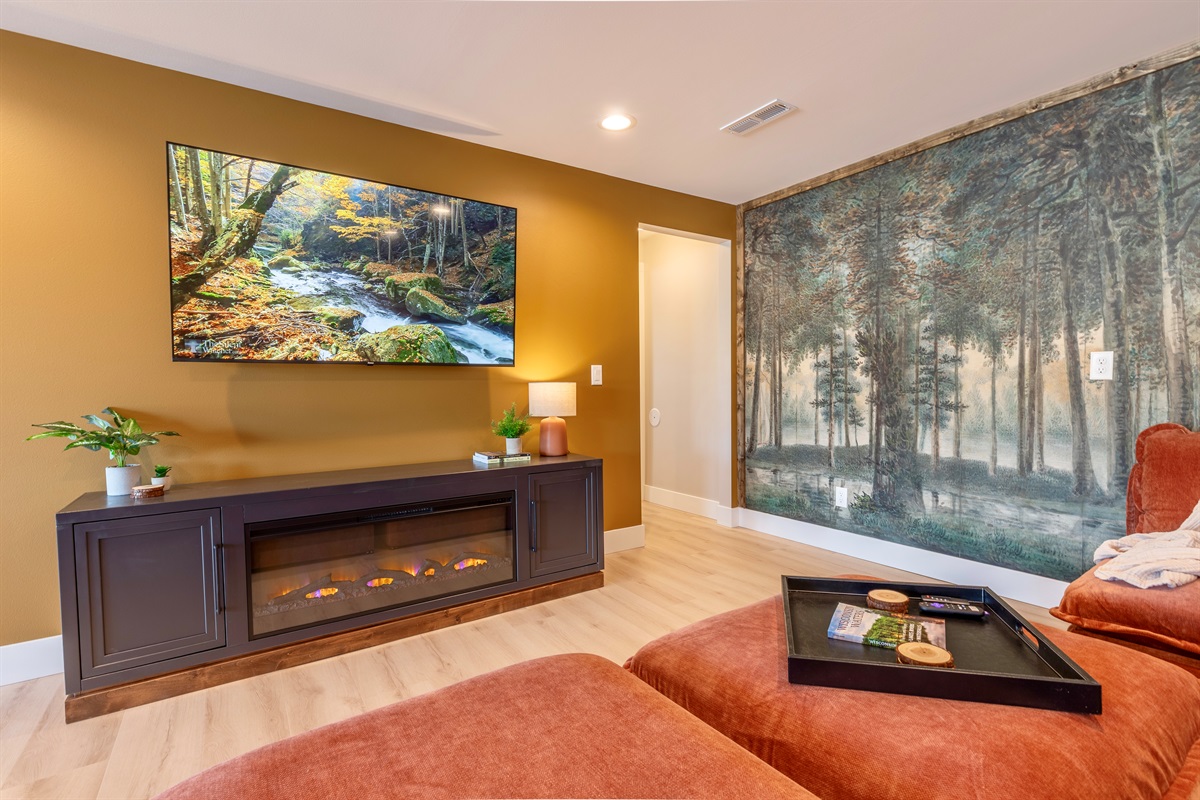 Downstairs open concept living area with large sectional sofa, electric fireplace and Roku TV.