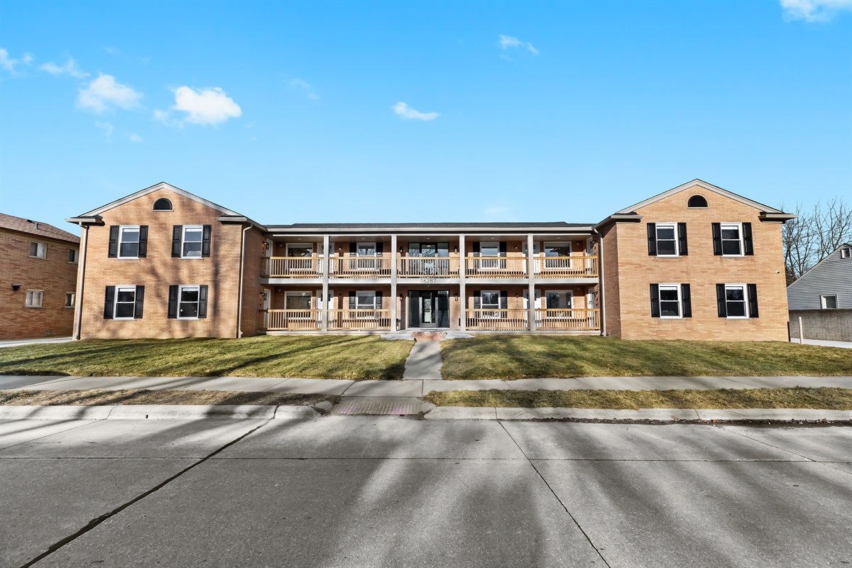 Charming brick apartment building with a welcoming entrance, private balconies, and a peaceful setting—offering a comfortable and convenient place to stay.