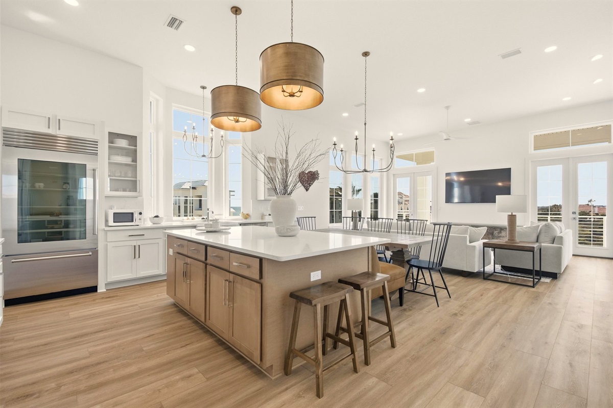 Beach days start here: everyone gathers at the big island to pack snacks, then comes back to this bright open space for showers, dinner, and a movie while the kids pass out on the couch—simple, easy, together.
