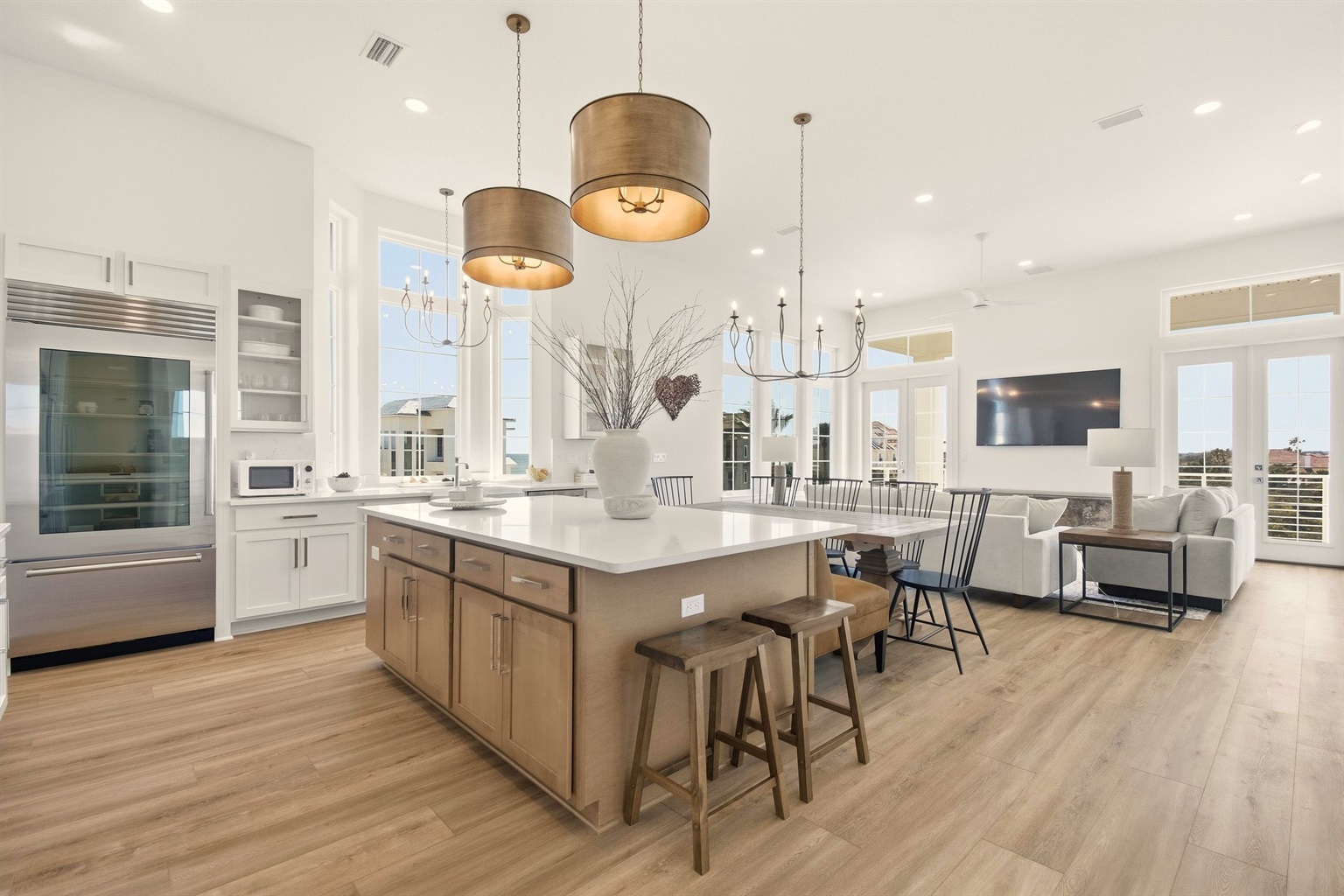 Beach days start here: everyone gathers at the big island to pack snacks, then comes back to this bright open space for showers, dinner, and a movie while the kids pass out on the couch—simple, easy, together.
