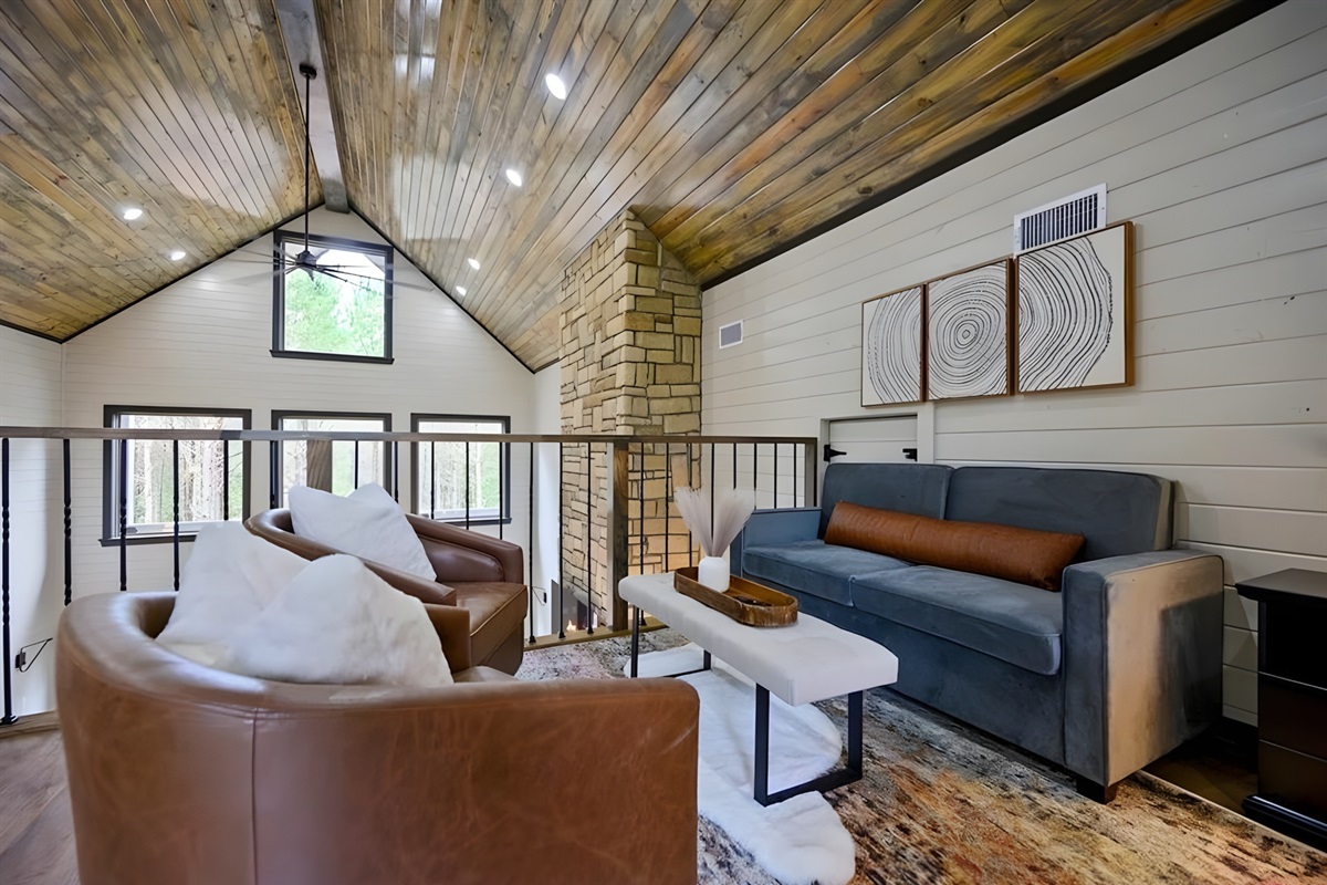 The open railing and wood-paneled ceiling give the loft a cozy cabin feel while still keeping it airy.