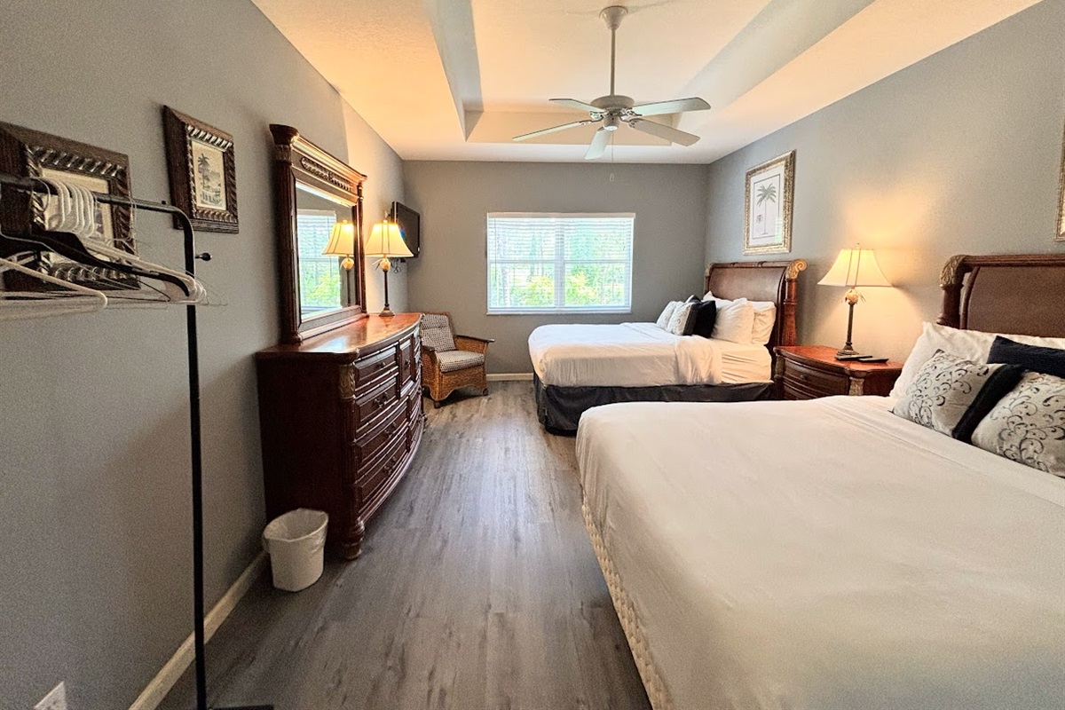 Spacious bedroom with two beds, wood-look flooring, dresser storage, and a relaxing setup.