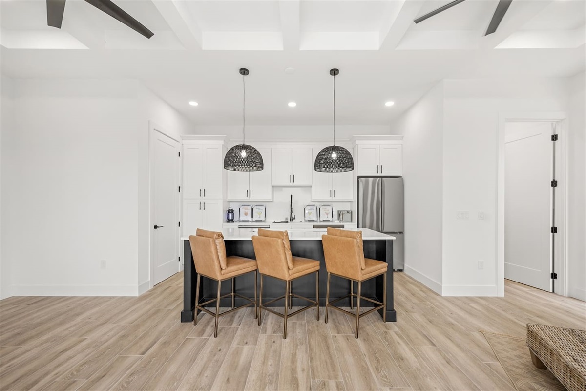 Featuring stylish chairs, granite tables with lit countertops, a chandelier fan, a refrigerator, and sleek flooring, creating a sophisticated and inviting space for gatherings or relaxation.