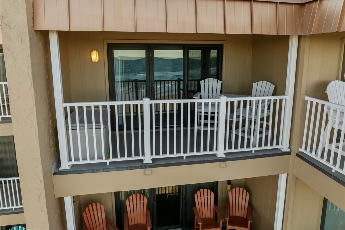 Private covered balcony with Adirondack seating, overlooking the beach and ocean beyond