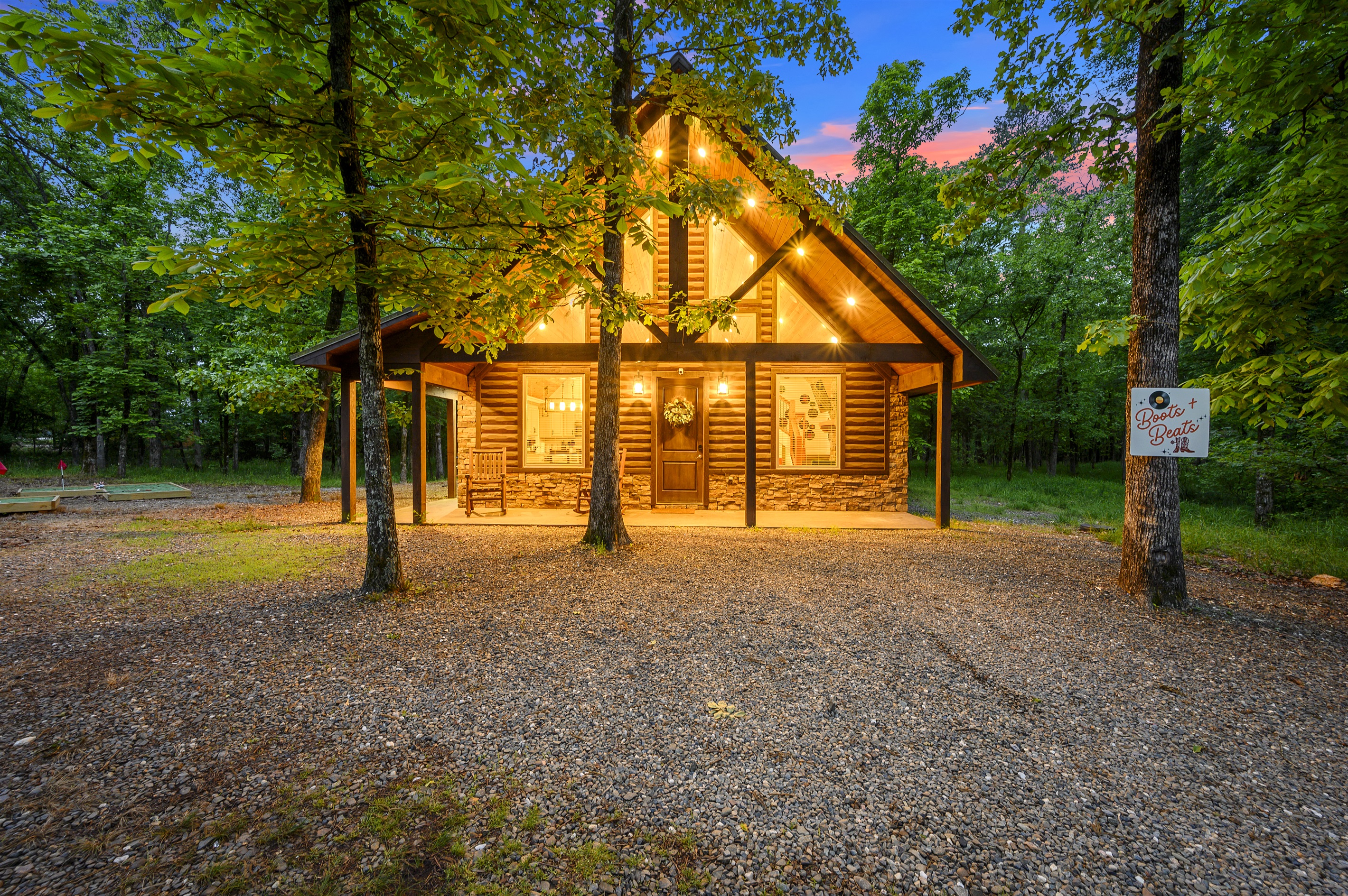 Boots & Beats cabin exterior surrounded by trees in central Hochatown.