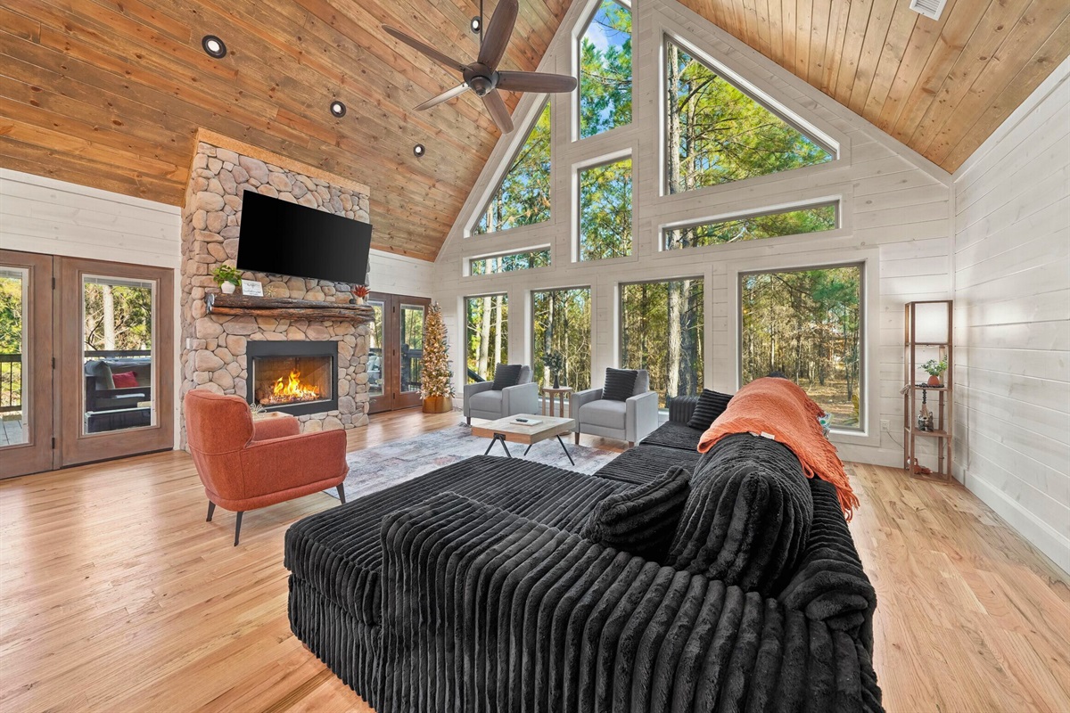 Living area with large windows, sectional sofa, and forest views.