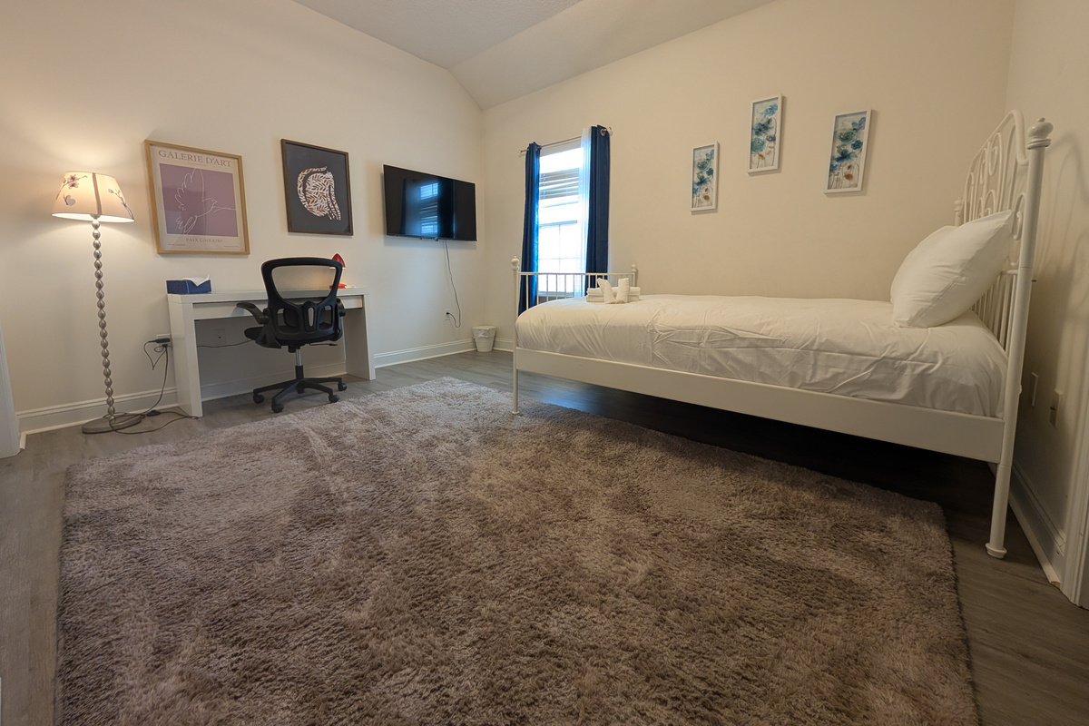 Bright guest bedroom with a dedicated workspace and TV &mdash; great for longer stays or remote work.