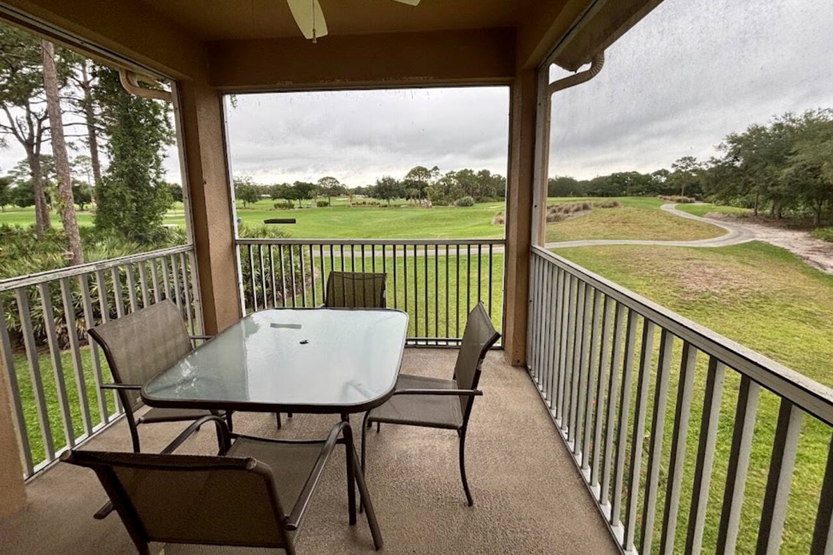 Private screened balcony with outdoor dining space and relaxing views of the surrounding green space.