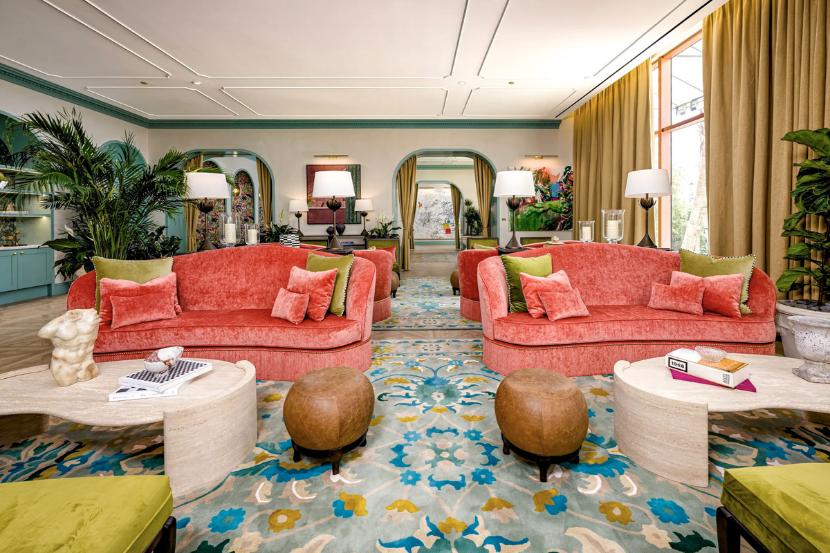 A lush conservatory lounge with coral sofas, towering palms and arched architecture - resort living, refined.