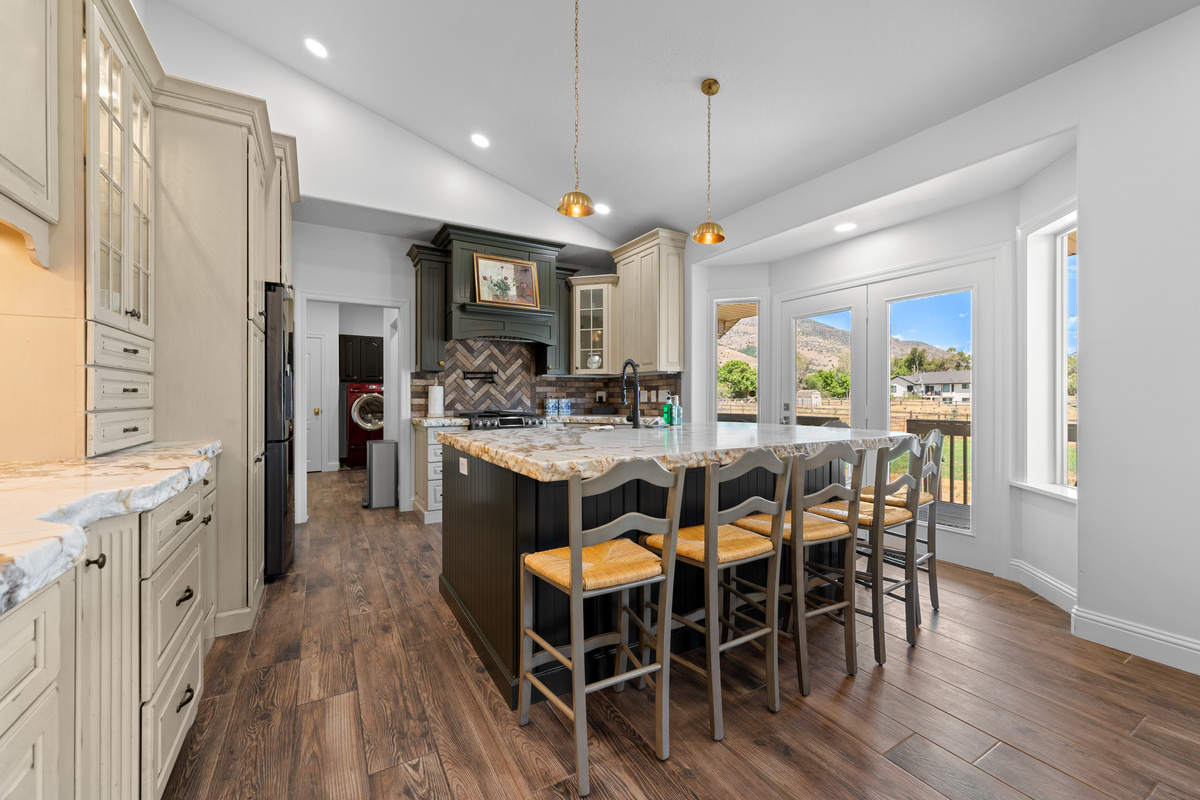 The beautifully designed kitchen features a substantial central island, custom cabinetry, stone countertops, and seating for casual meals or conversation.