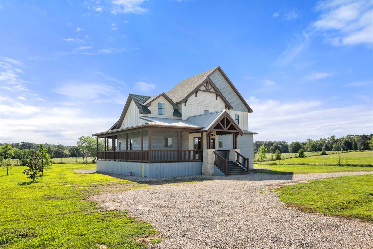 Charming lodge-style exterior with wraparound porch and countryside setting.