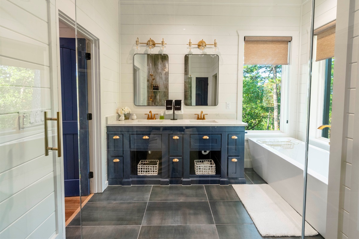 Luxury bathroom featuring double vanity, soaking tub, and elegant modern finishes