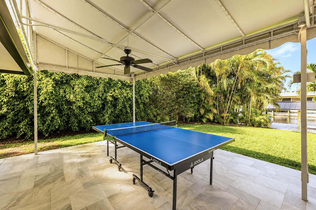 The ping-pong table is set up for easy games on the covered patio, close to the pool and outdoor seating.