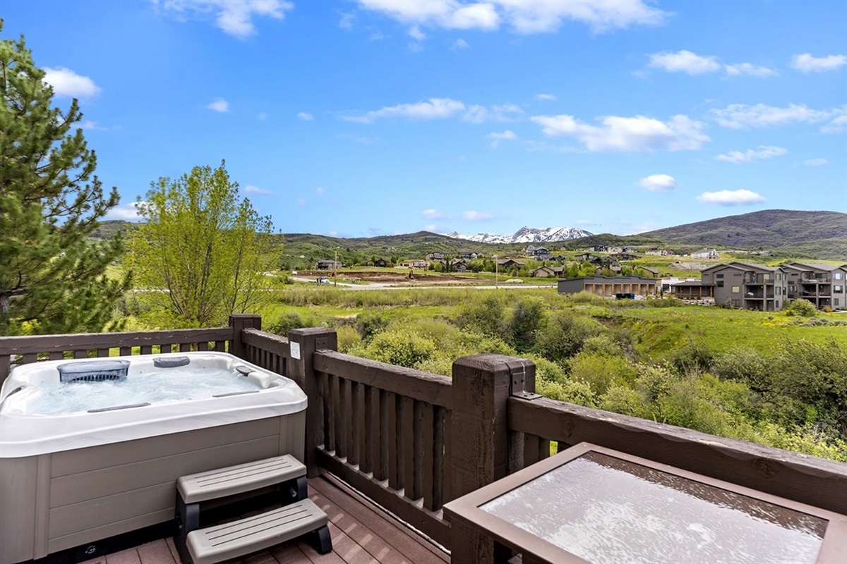 An elevated outdoor living experience awaits on the private deck, where a bubbling hot tub and panoramic mountain views set the stage for pure relaxation.