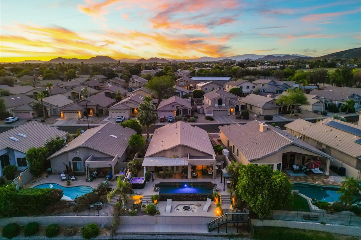 An aerial view that puts it all in perspective — your home sits right on the lake, with a glowing pool out back and the mountains painted in the sunset sky. Pure Arizona magic.