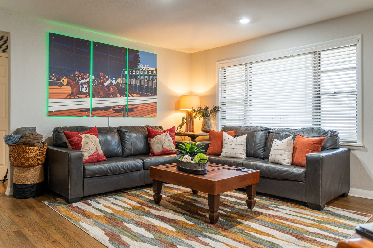 Settle in under the Oaklawn silks — the racing art lights up and the room leans all the way into where you are.