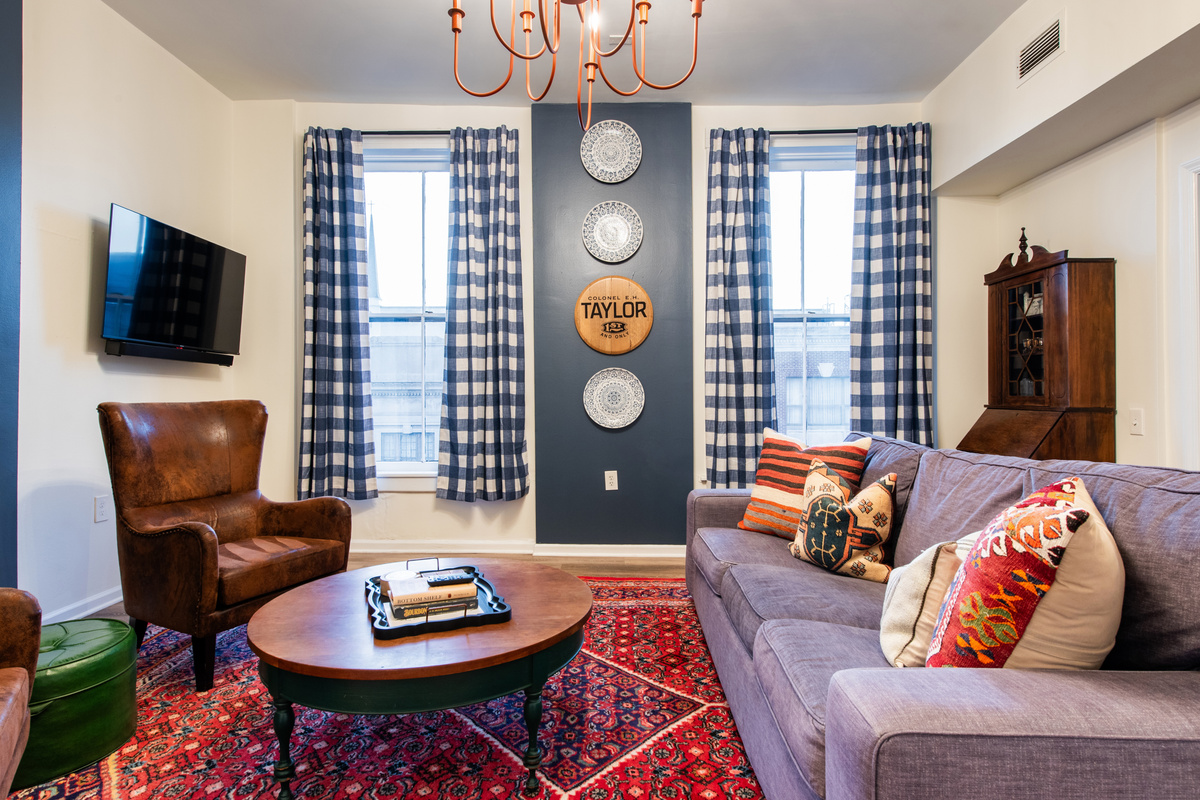 The EH Taylor Suite living room, with a sofa, leather chair and patterned rug.