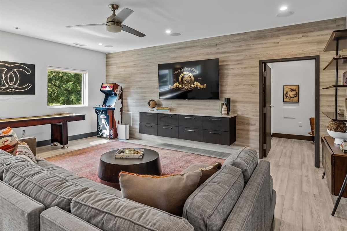 Game room with couches, tv, and attached bath with shower.