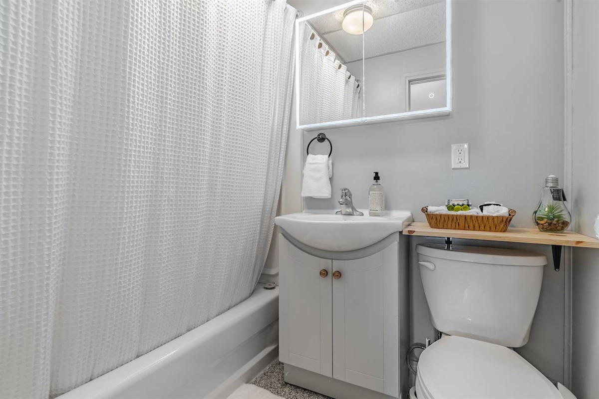 Basement full bathroom with tub/shower and lighted mirror.