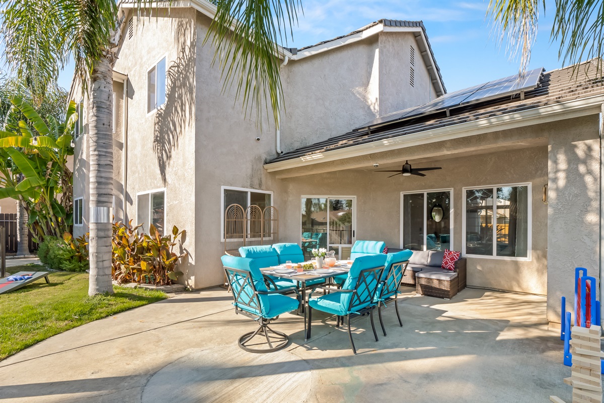 Large covered patio with comfortable seating and outdoor dining—perfect for family meals, game nights, and relaxing while the kids play in the yard.