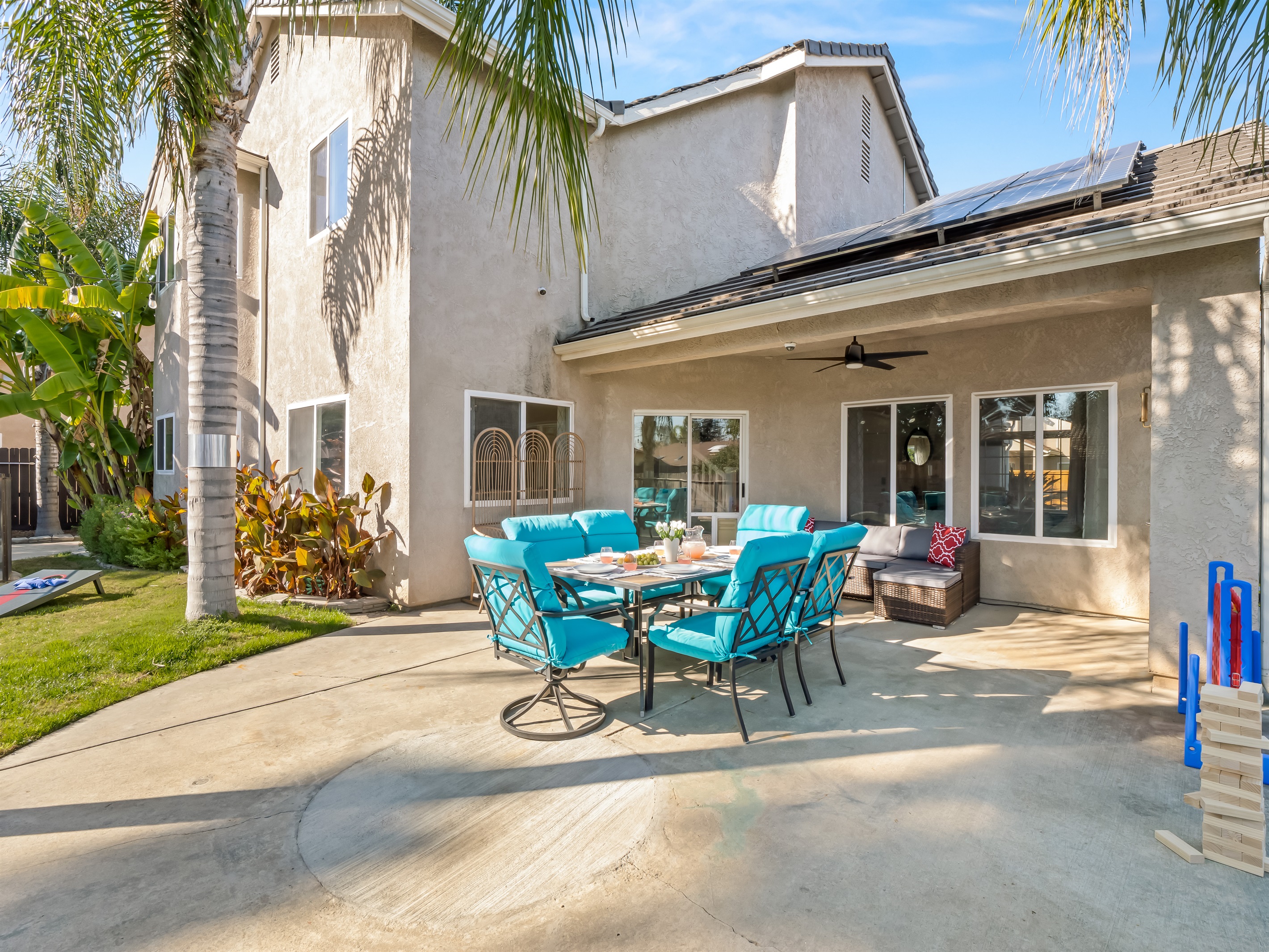Large covered patio with comfortable seating and outdoor dining—perfect for family meals, game nights, and relaxing while the kids play in the yard.
