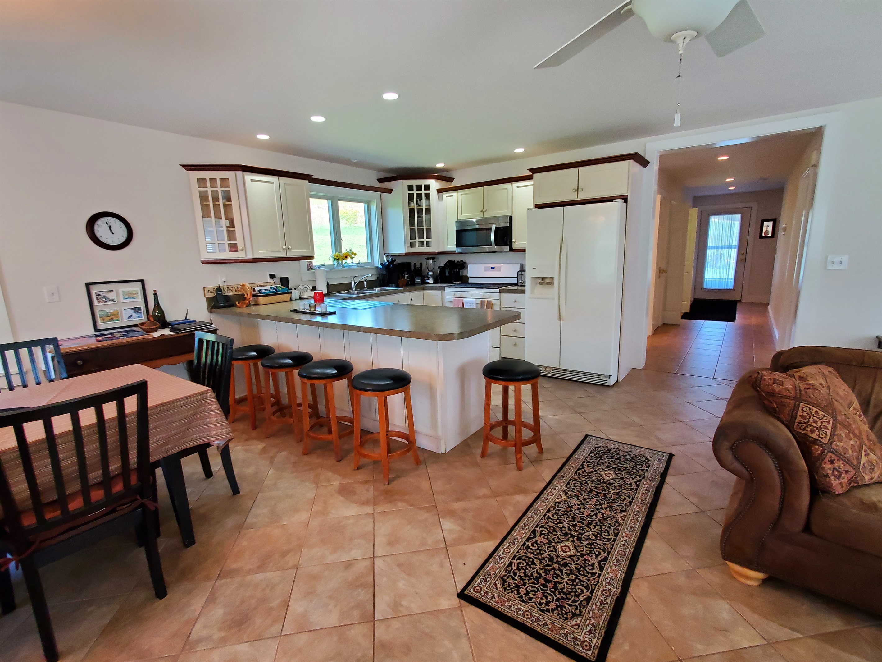 Open living, dining and kitchen area, seating at the kitchen peninsula.