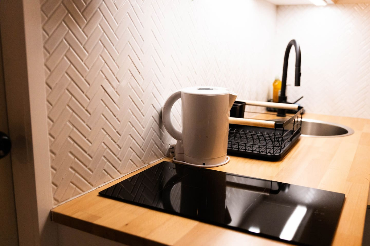 The kitchen has a 2 element induction stove, a microwave,  a mini fridge/ freezer, a sink,  a kettle, pots/ pans, utensils etc.