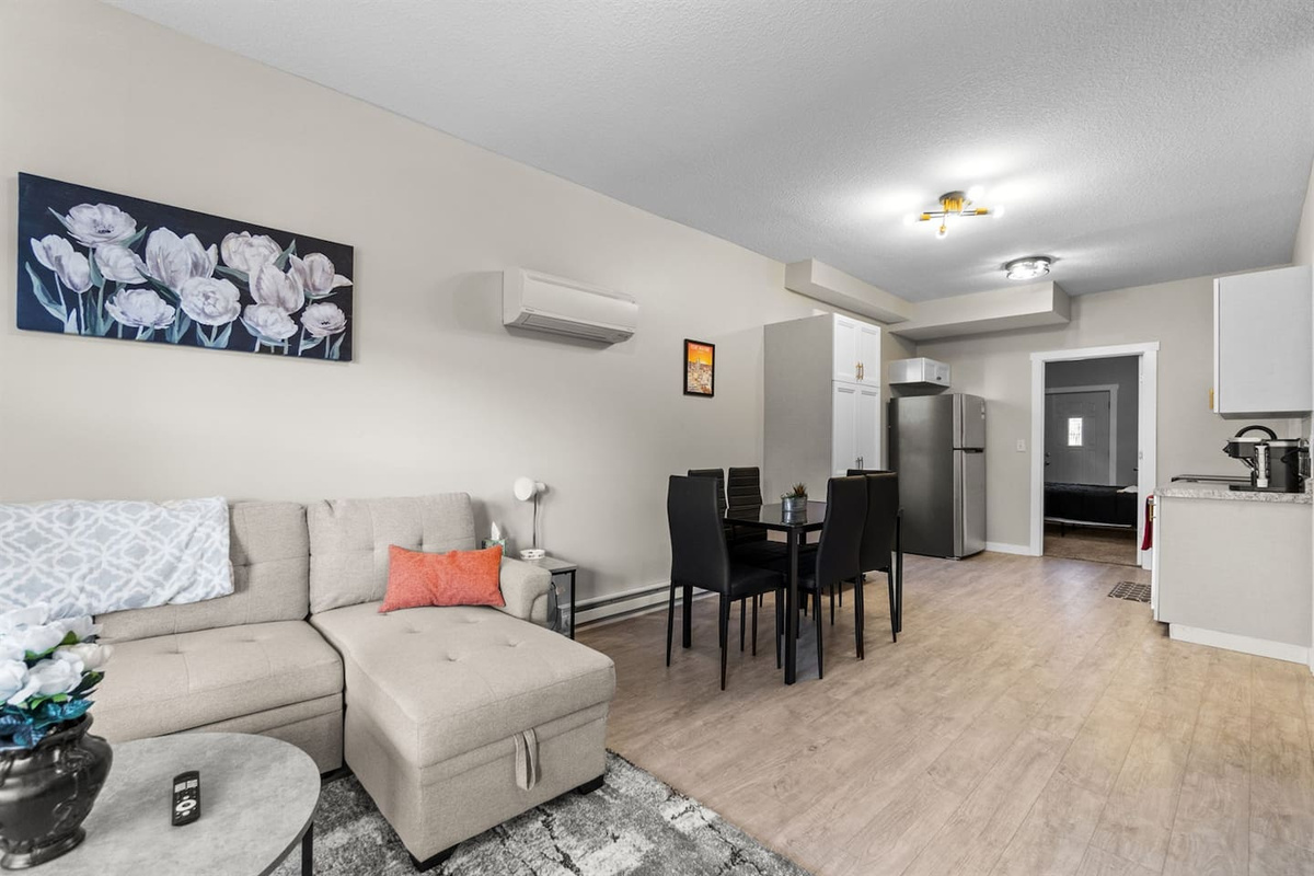 Open-concept living room with a sectional sleeper sofa, leading seamlessly into the dining area and modern kitchen for a spacious, connected feel.
