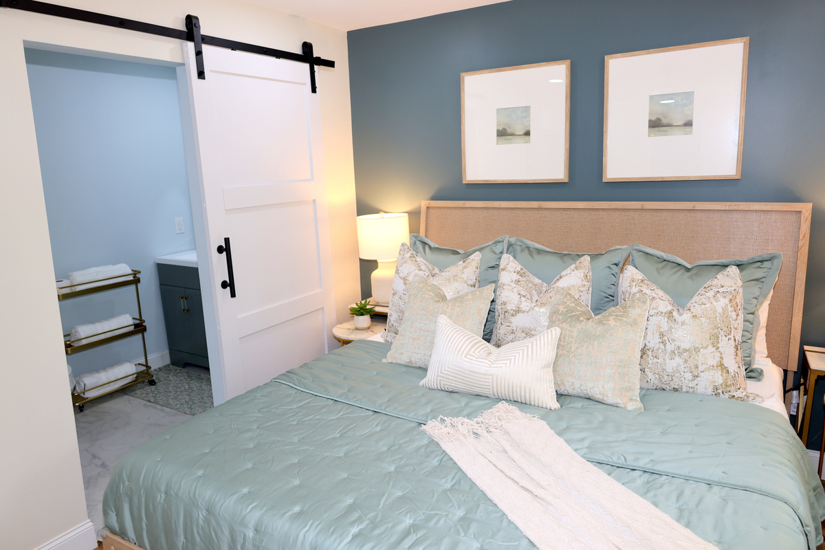 Beautiful bedroom with accent wall, barn door detail, luxury bedding, and ensuite bathroom access