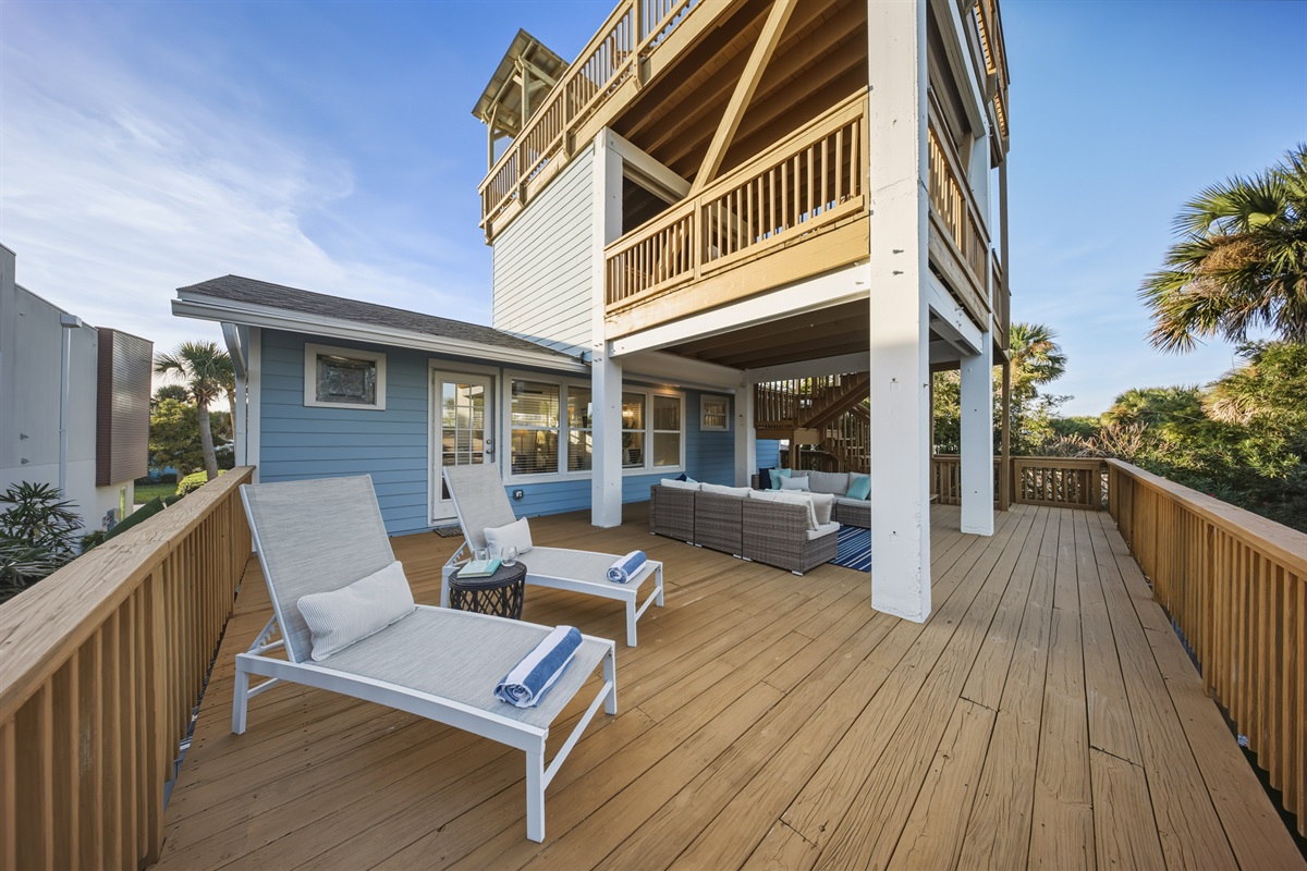 Spacious porch off master suite with cozy seating area and loungers with palm views
