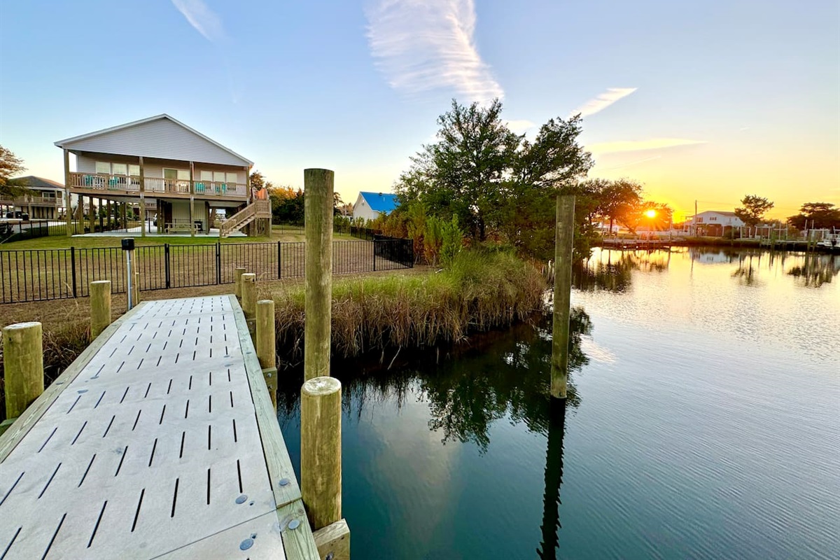 Private backyard dock with boat lift and fillet table, fenced-in backyard, fire pit with Adirondack chairs, hammocks, propane grill, picnic table, outdoor shower, expansive waterfront back deck, neighborhood boat ramp and dock
