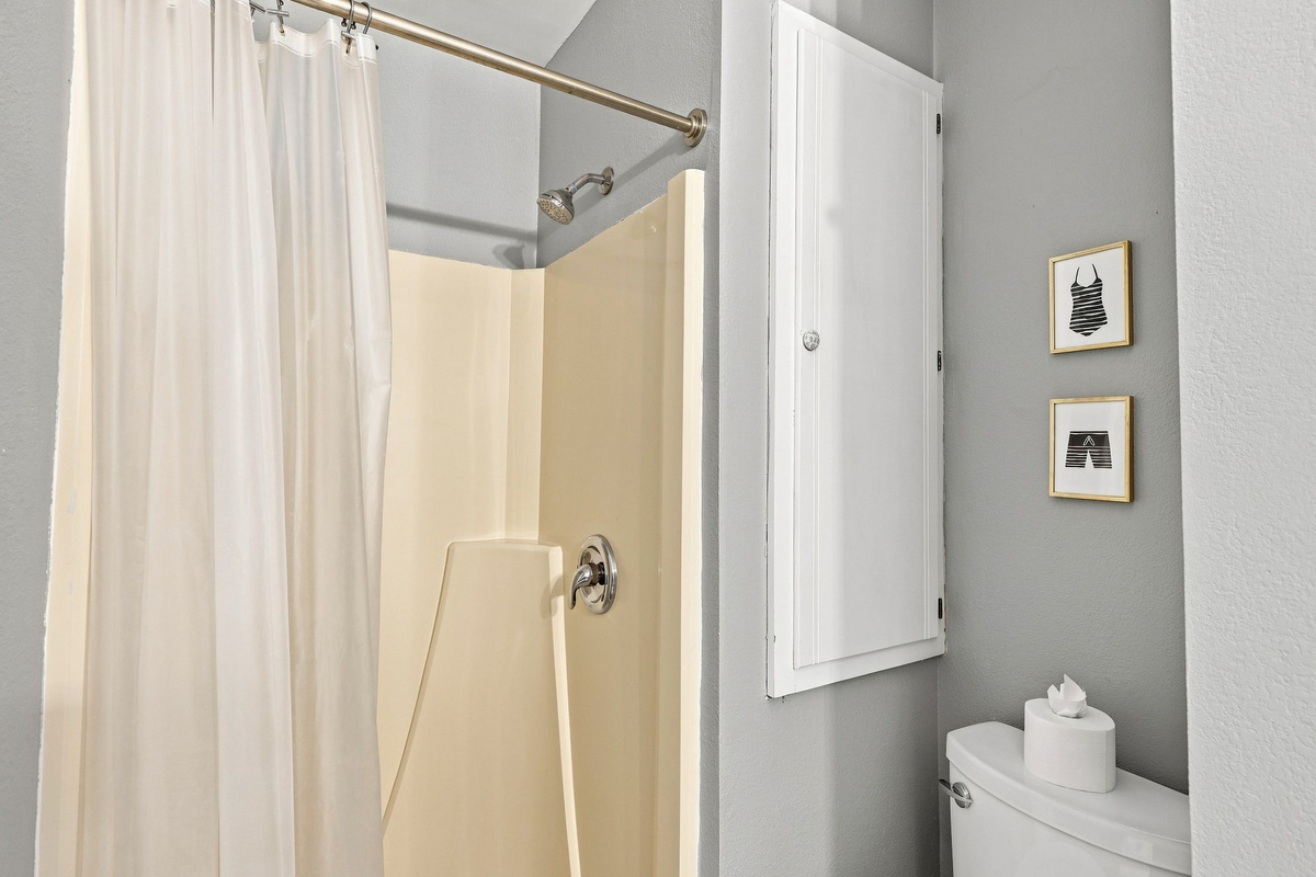 A functional full bathroom setup complete with built-in storage and sweet beach-themed wall art.