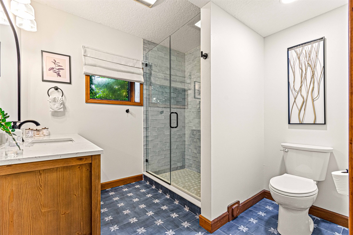 Bright and stylish bathroom with a walk-in shower, wood accents, and cheerful patterned tile floors.🚿