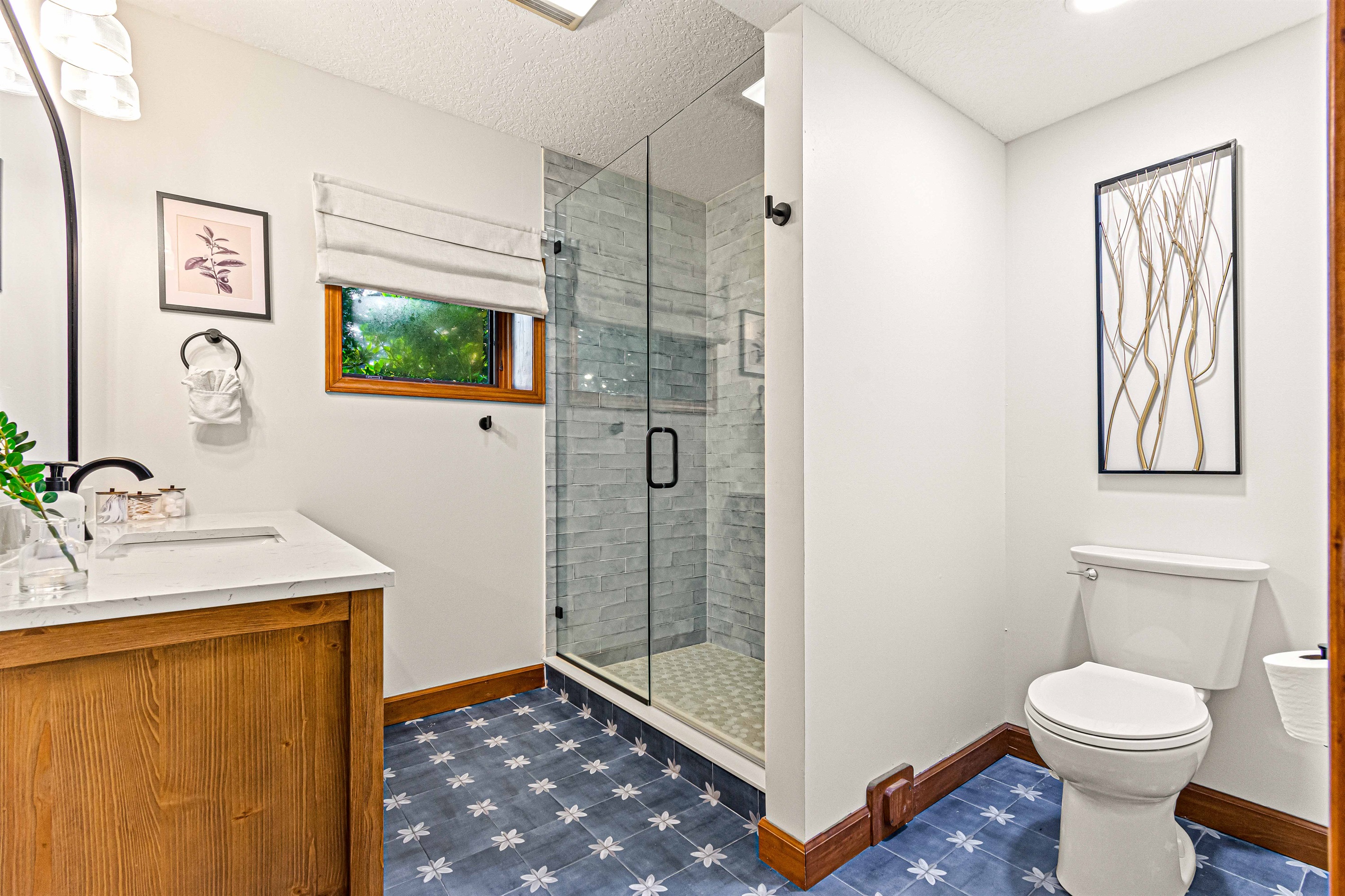 Bright and stylish bathroom with a walk-in shower, wood accents, and cheerful patterned tile floors.🚿
