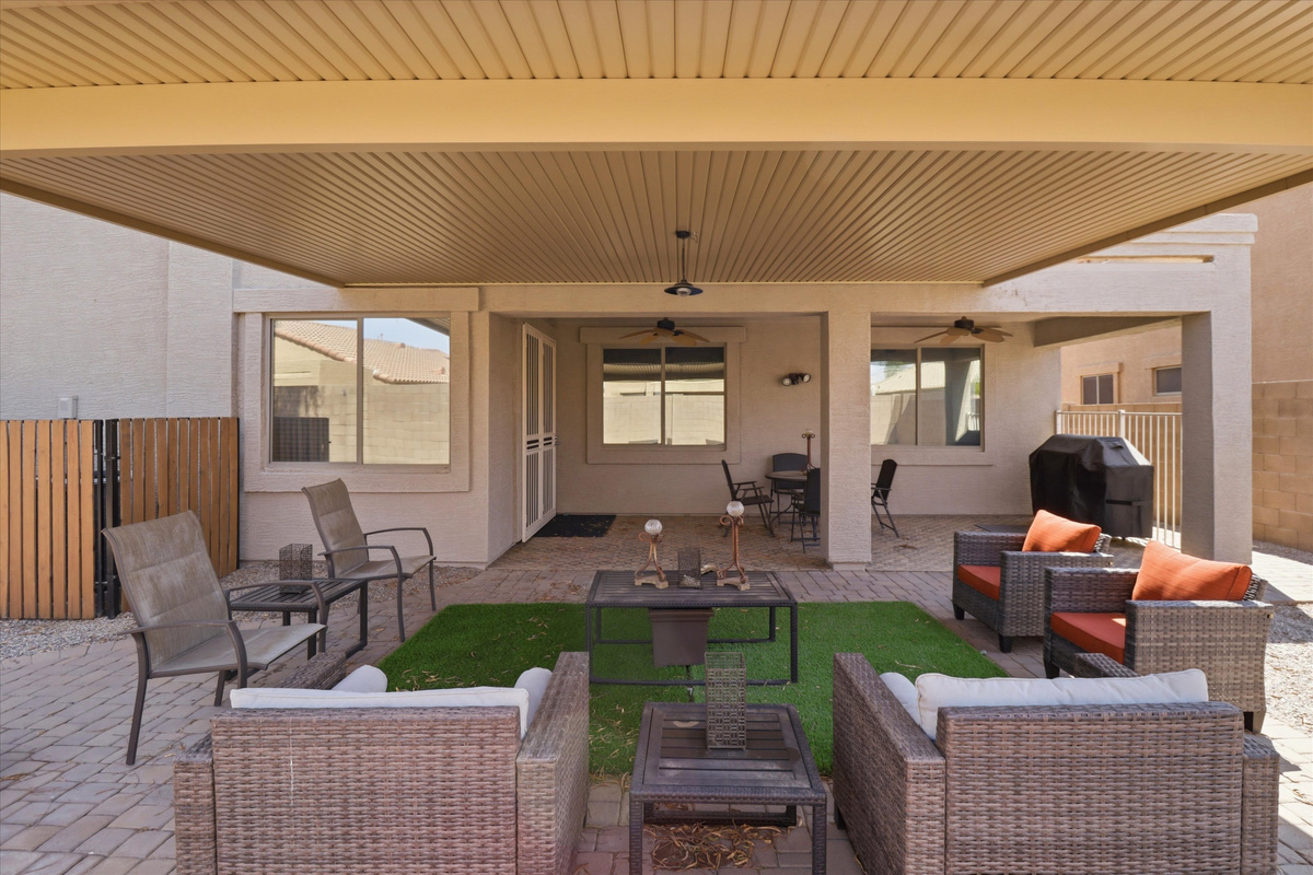 Covered backyard patio with lounge seating, BBQ grill, and space to hang out outside.