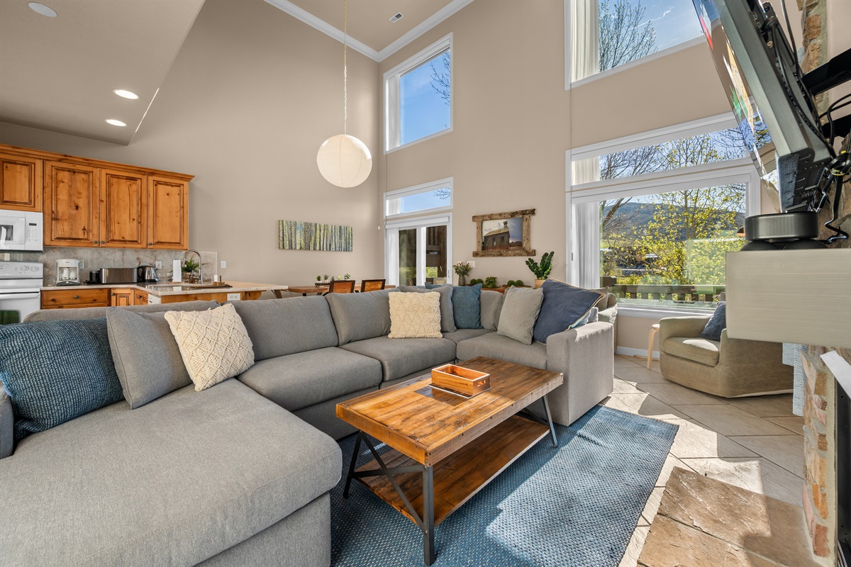 Bright and welcoming living room with soaring ceilings, oversized windows, and cozy mountain-modern comfort.