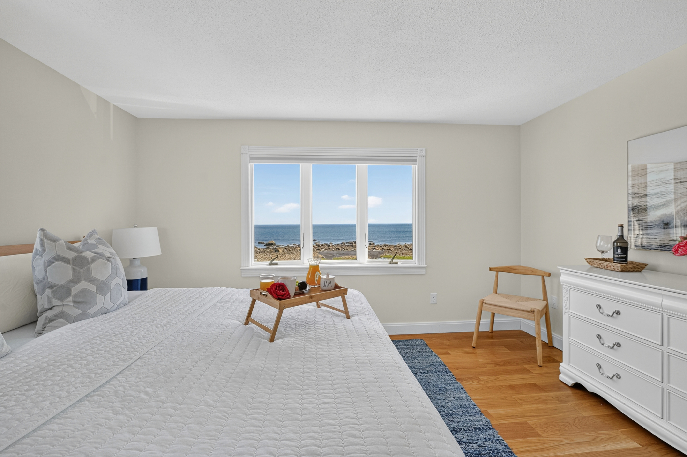 Relax in a comfortable bedroom with a large window bringing the coastal landscape right into view.