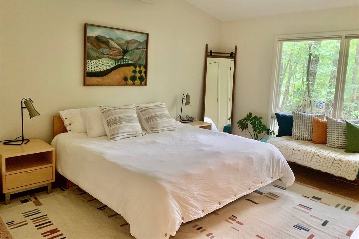 The master bedroom's king platform bed features luxurious cotton sheets and a linen duvet cover. Room & Board night stands, original art, and Article Mirror. Oh, and throw pillows. Lots of throw pillows. Pillow fight? Just kidding.