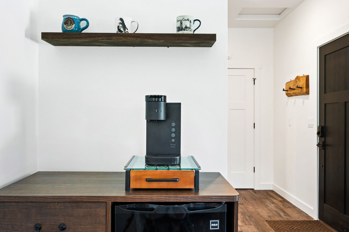 Brew your favorite cup at the in-room coffee bar, stocked with a Keurig, mini-fridge, and Door County mugs on a rustic floating shelf.