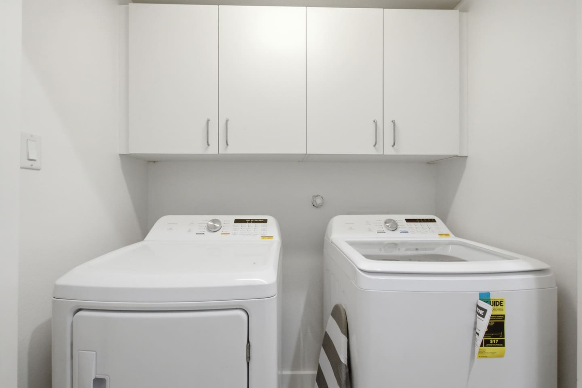 In-unit washer and dryer with overhead cabinetry and dedicated laundry space. A practical amenity that makes longer stays and light packing genuinely easy for every guest.

