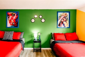 A sleek lamp casts a gentle light against a soothing green wall, highlighting two captivating wall paintings