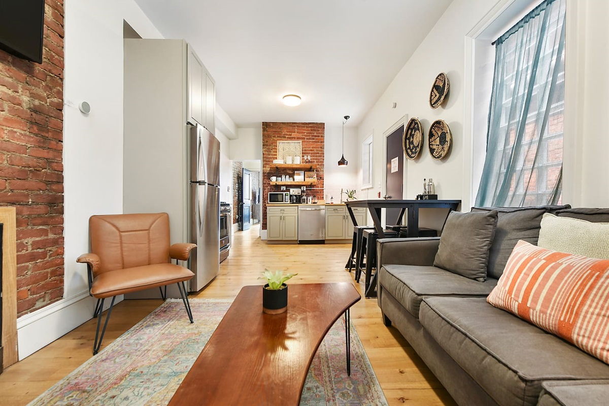 Unwind in comfort! This cozy space features a plush couch, an extra chair, a stylish coffee table, and a soft rug—all bathed in natural light from a huge window. Perfect for relaxing after a day of exploring!