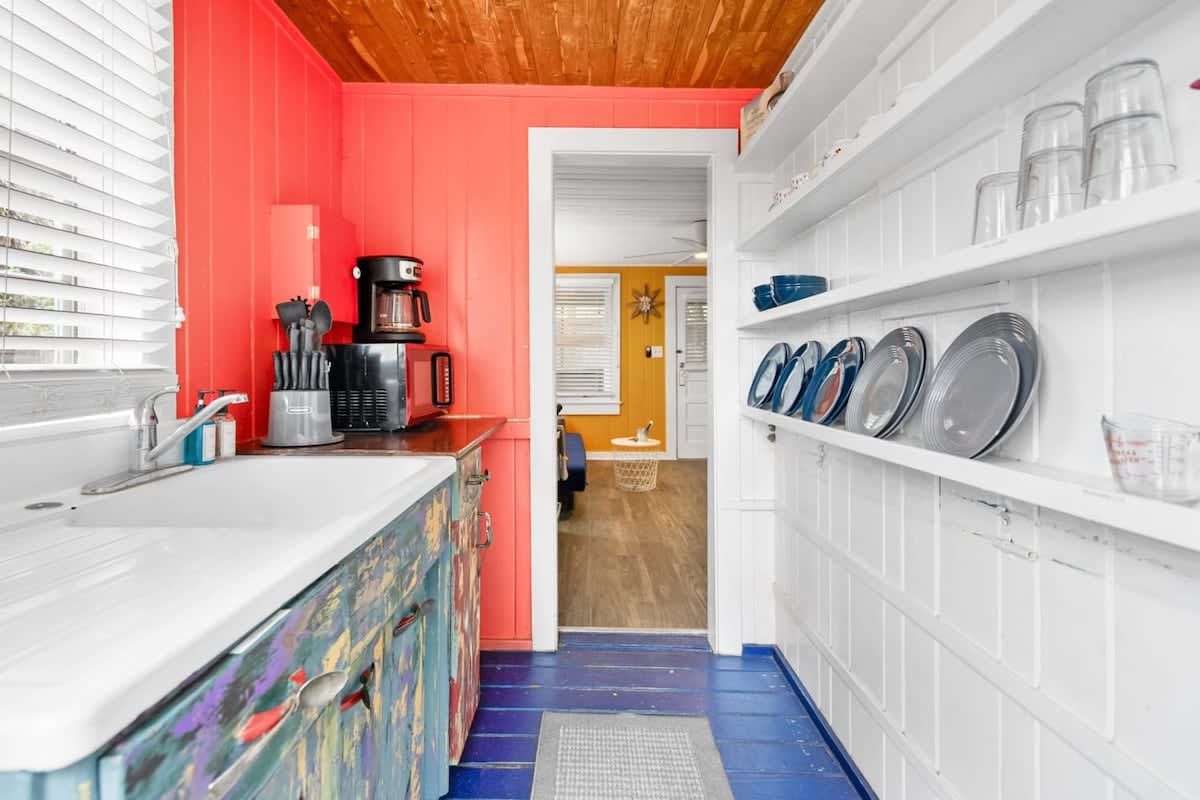 Deep red walls, white counters and the coffee maker ready for the morning. Compact, cheerful and genuinely usable, though do note there is no dishwasher here, so it is hands in the sink and somebody on drying.