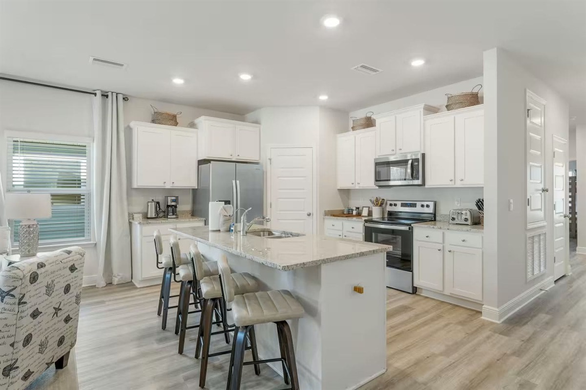 Modern kitchen with a 4-stool counter, microwave, stove, and spacious 2-door fridge