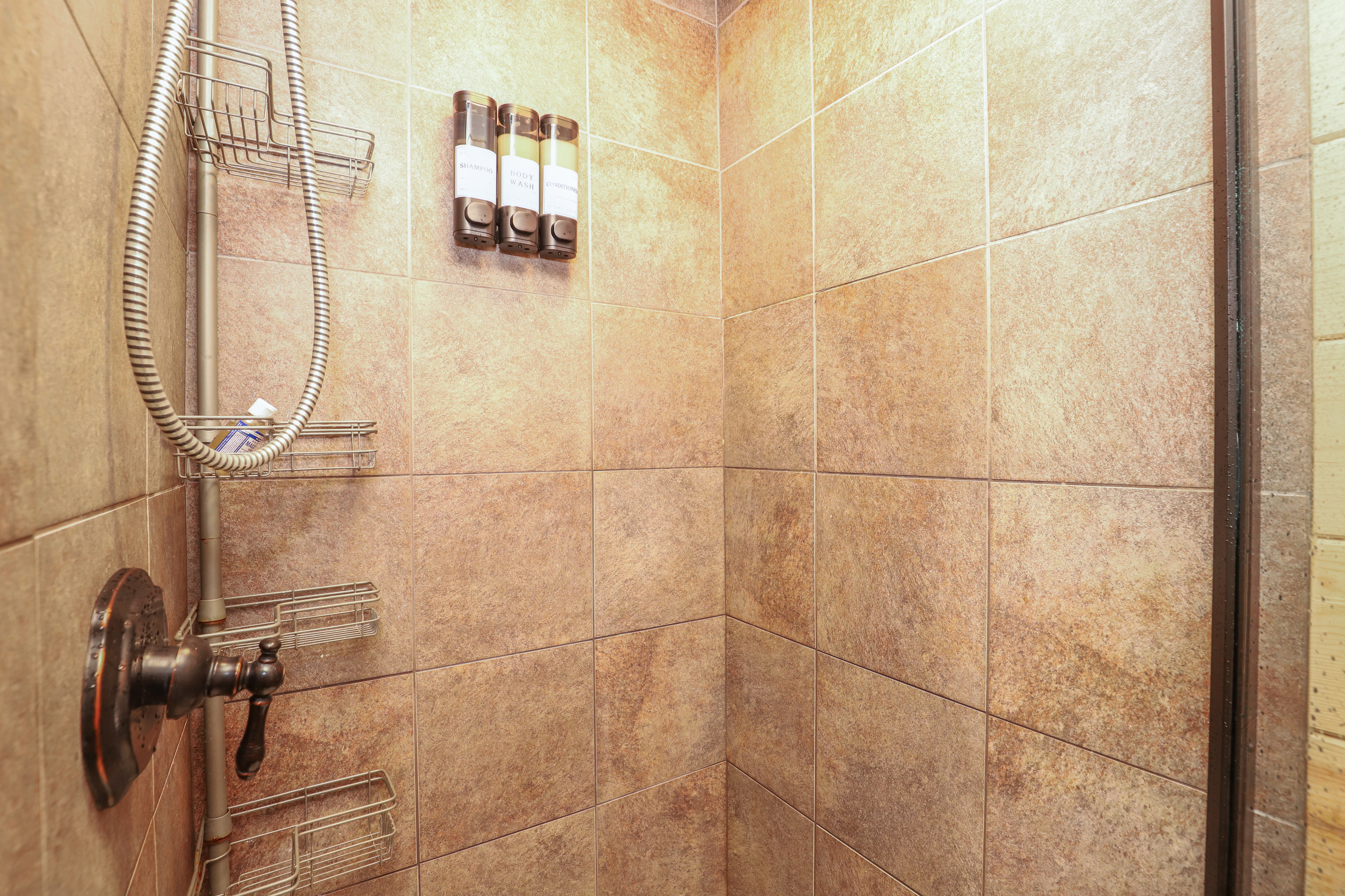 Glass Enclosed Tile Shower w/ Body Wash, Shampoo & Conditioner Dispensers and removable shower head.