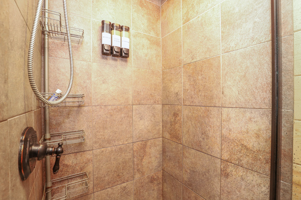 Glass Enclosed Tile Shower w/ Body Wash, Shampoo & Conditioner Dispensers and removable shower head.