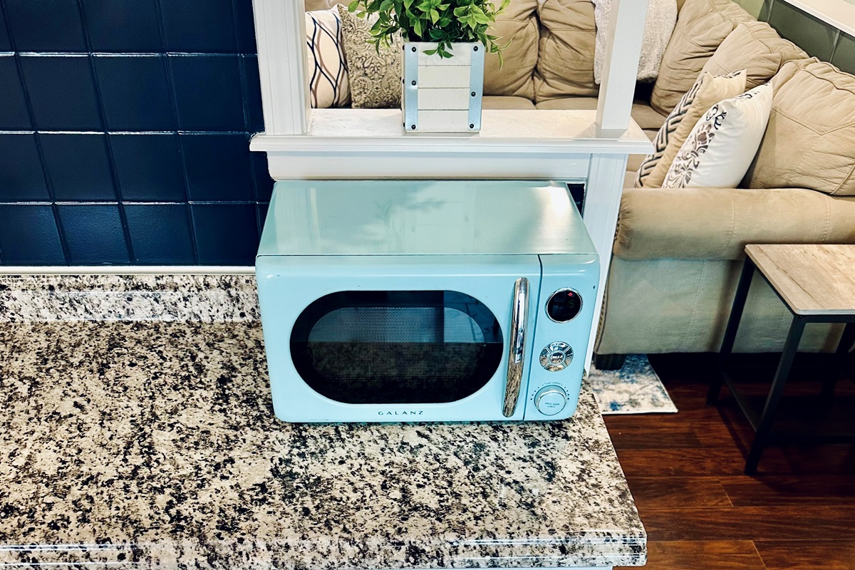 Kitchen drawers organized with paper plates, bowls, disposable cups, utensils, and napkins, along with food storage bags, aluminum foil, plastic wrap, wax paper, and trash bags—convenient extras for longer stays.