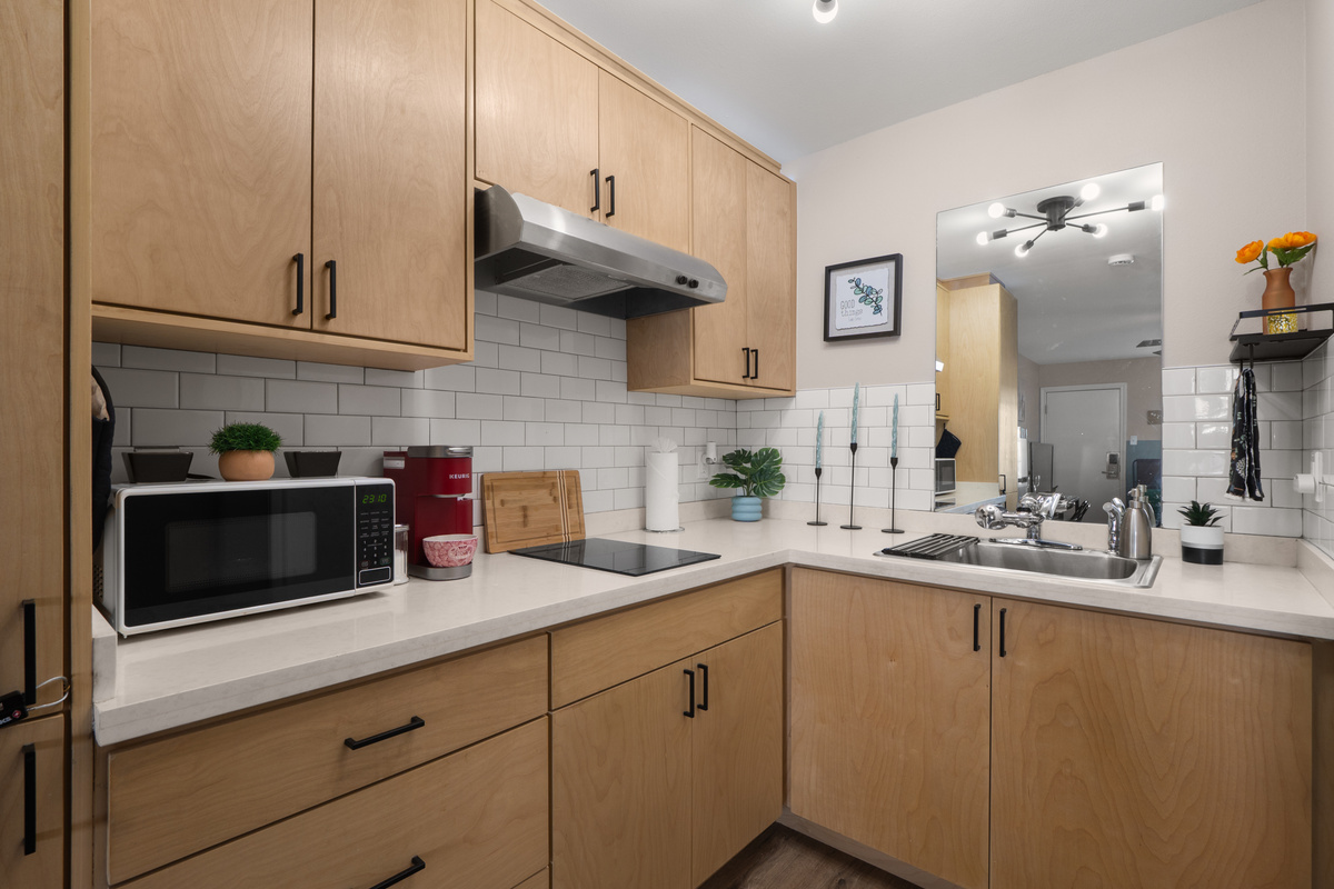 Kitchenette with microwave, cooktop, sink, and cabinet storage for simple meals.

